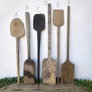 Könnte beinhalten: Sechs Holzschöpflöffel in verschiedenen Längen und Formen. Die Schöpflöffel sind alle aus Naturholz gefertigt und haben ein rustikales, gealtertes Aussehen.