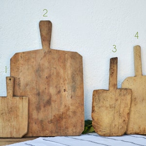 Puede incluir: Cuatro tablas de cortar de madera de diferentes tamaños y formas. Las tablas son todas de madera natural y tienen un aspecto rústico y vintage.
