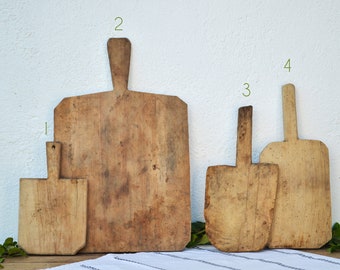 May include: Four wooden cutting boards of varying sizes and shapes. The boards are all made of natural wood and have a rustic, vintage look.