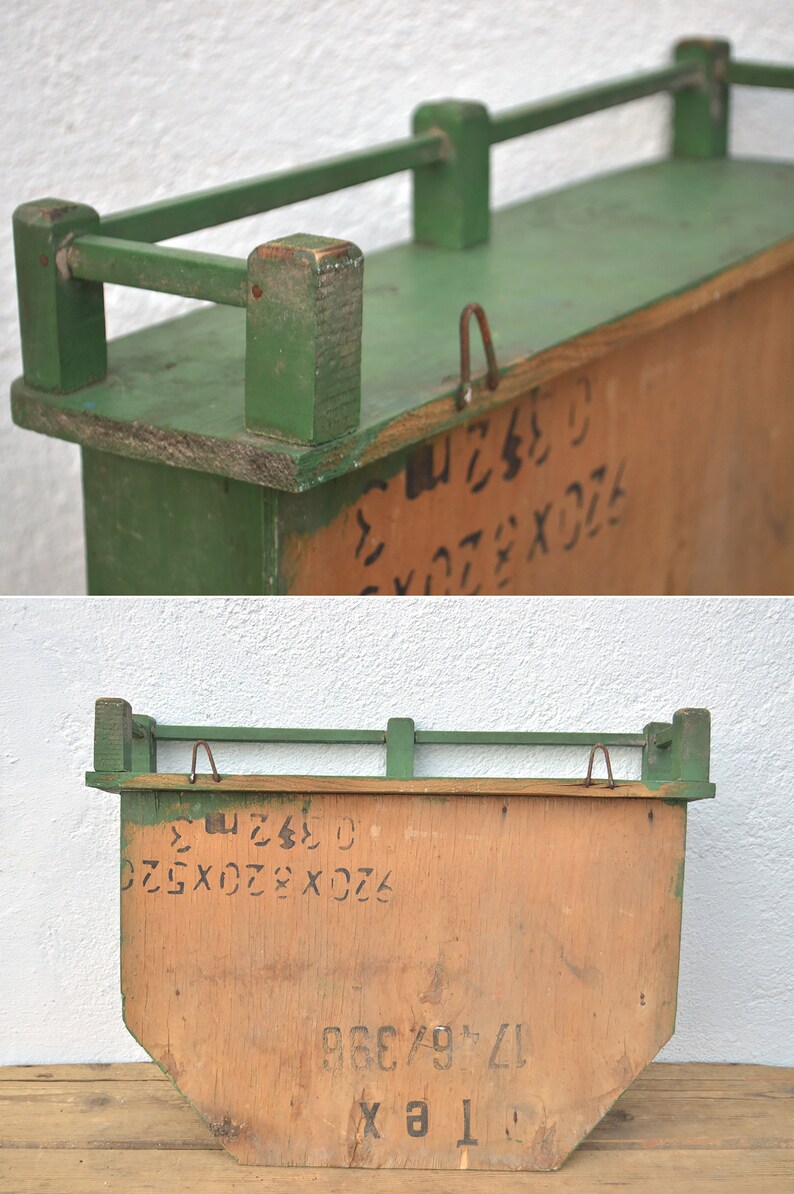 May include: A green wooden shelf with a metal railing. The shelf has a wooden back with handwritten numbers and letters. The shelf is 17.75 inches wide and 9.75 inches tall.