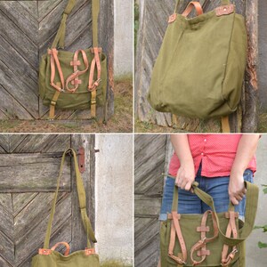 May include: A green canvas bag with brown leather straps and buckles. The bag has a long strap for carrying it over the shoulder.