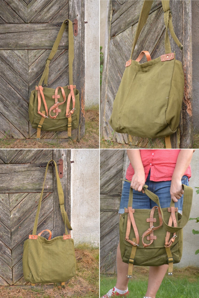 May include: A green canvas bag with brown leather straps and buckles. The bag has a long strap for carrying it over the shoulder.