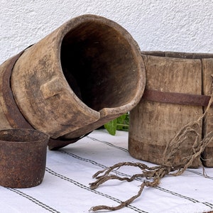 Primitive Wassereimer aus Holz, geschnitzt aus Baumstämmen und rostigem Metallbecher