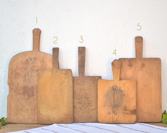 May include: Five vintage wooden cutting boards with handles. The boards are various sizes and shapes, with a natural wood finish.