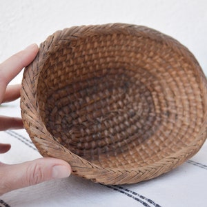 May include: A woven brown wicker basket with a rounded oval shape.