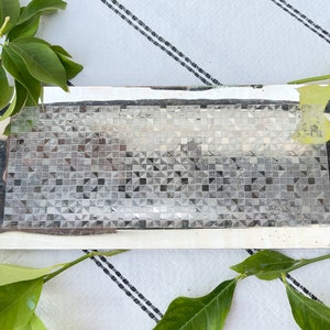 May include: A silver rectangular serving tray with a geometric pattern. The tray is made of metal and has a shiny finish.