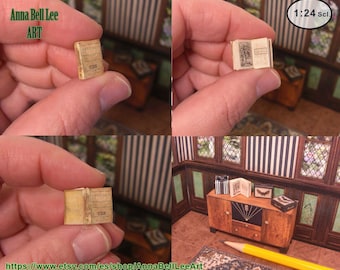 May include: Miniature book with aged paper pages and cover. The book is held in a hand, showcasing its small size. The text "Anna Bell Lee ART" is visible in the image. The book is part of a collection of miniature items.