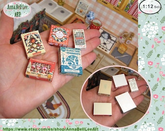 May include: Miniature Christmas ornament boxes in various designs, including a box with the text "Shiny & Brite". The boxes are held in a hand, with a miniature kitchen scene in the background. The text "Anna Bell Lee ART" is visible.