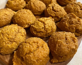May include: A wooden board filled with small, round, golden brown pumpkin cookies.