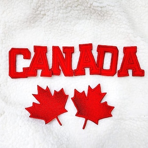 May include: Red embroidered applique with the word "CANADA" and two red maple leaf patches on a white, textured background. The letters are in a bold, block style.
