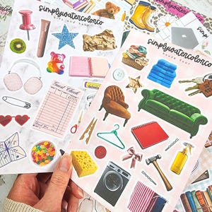 Könnte beinhalten: Eine Sammlung dekorativer Aufkleber mit verschiedenen Designs, darunter eine rosa Reißzwecke, ein Stern, ein Teddybär, ein Notizbuch, Kopfhörer, ein Sofa, eine Waschmaschine und eine grüne Tragetasche. Die Aufkleber haben den Text "simplywatercolorco" und "bits and bobs".
