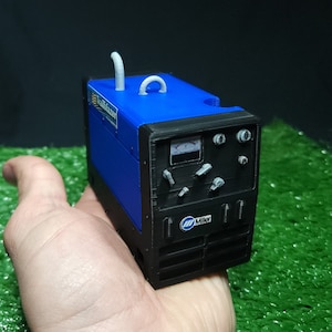 以下が含まれることがあります： 白いハンドルが付いた、青と黒の小さなミラーエレクトリック溶接機。溶接機は人の手に置かれています。