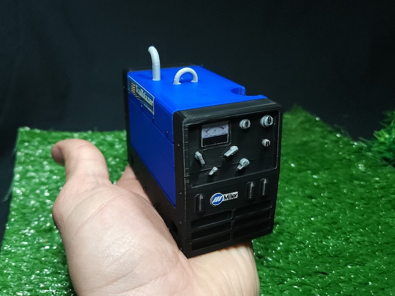 以下が含まれることがあります： 白いハンドルが付いた、青と黒の小さなミラーエレクトリック溶接機。溶接機は人の手に置かれています。
