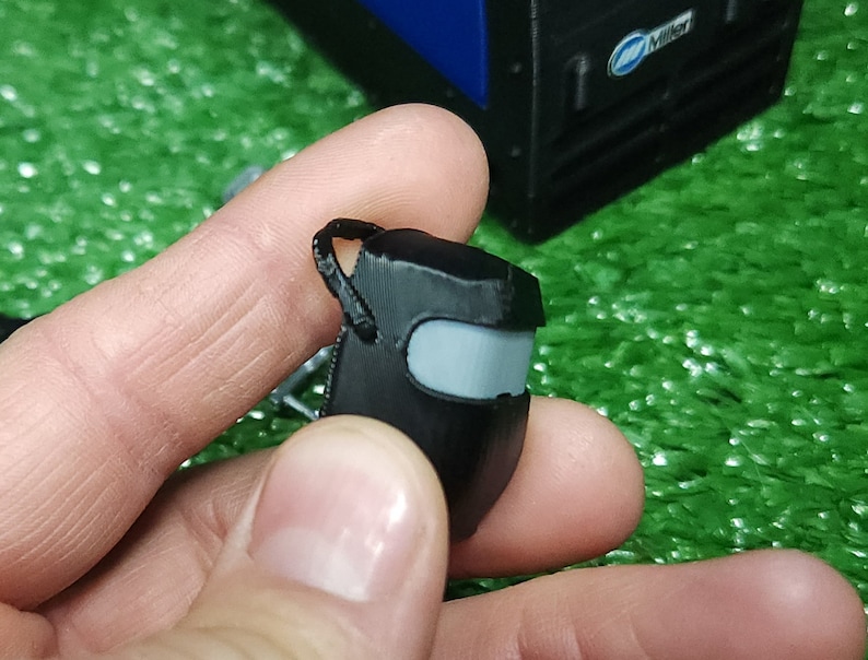以下が含まれることがあります： グレーのバイザーが付いた黒いプラスチック製の溶接マスク。マスクは小さく、おもちゃのようです。