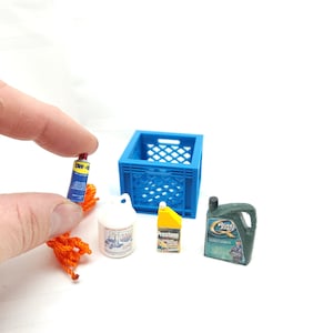 Könnte beinhalten: Eine blaue Plastikkiste mit verschiedenen Miniatur-Haushaltsartikeln, darunter eine Flasche Reiniger, eine Dose Kühlmittel, eine Flasche Motoröl, eine Sprühdose und eine Rolle orangefarbenes Seil.