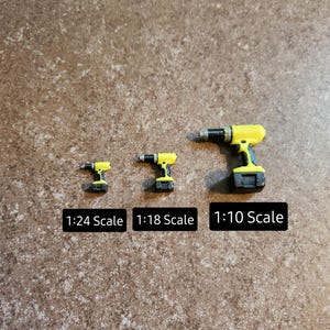 May include: Three yellow and black toy power drills in different sizes, labelled 1:24 Scale, 1:18 Scale, and 1:10 Scale.