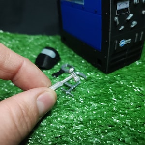 以下が含まれることがあります： 丸い頭と長いハンドルを持つ銀色の金属製の工具。工具は手で持たれています。