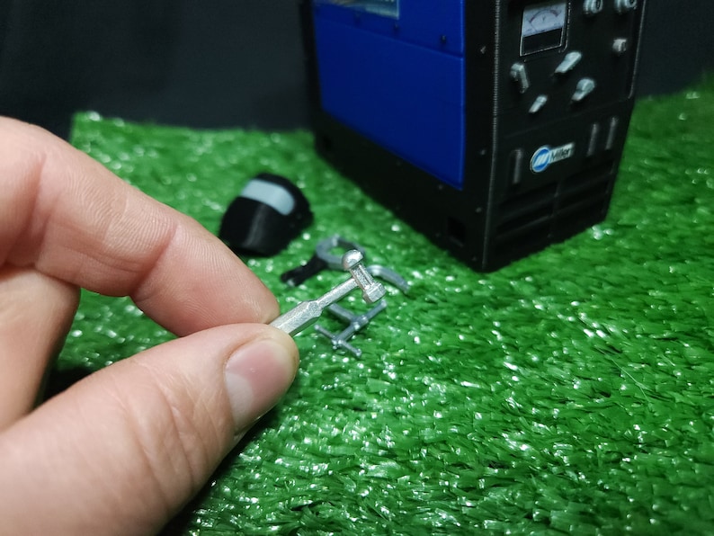 以下が含まれることがあります： 丸い頭と長いハンドルを持つ銀色の金属製の工具。工具は手で持たれています。