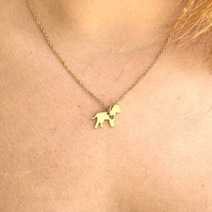 May include: A gold chain necklace with a small gold pendant shaped like a dog with a heart inside.