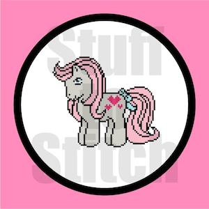 May include: A pixelated illustration of a pink pony with a blue bow and pink hearts on its flank. The pony is standing on a white background inside a black circle.