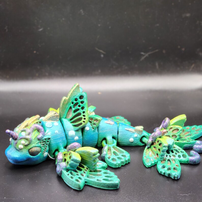 Puede incluir: Una figurita de drag&oacute;n articulada verde y azul con alas de mariposa. El drag&oacute;n tiene una superficie detallada y texturizada y est&aacute; hecho de pl&aacute;stico.