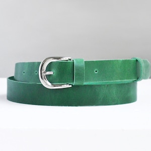 May include: A green leather belt with a silver buckle. The belt is rolled up and the buckle is in the center of the image.