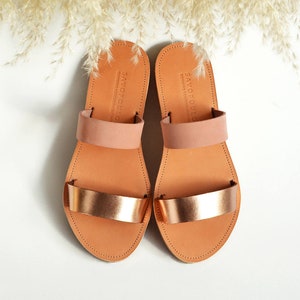 Puede incluir: Un par de sandalias de cuero marr&oacute;n con correas de oro rosa. Las sandalias tienen un dise&ntilde;o sencillo y son perfectas para el verano.