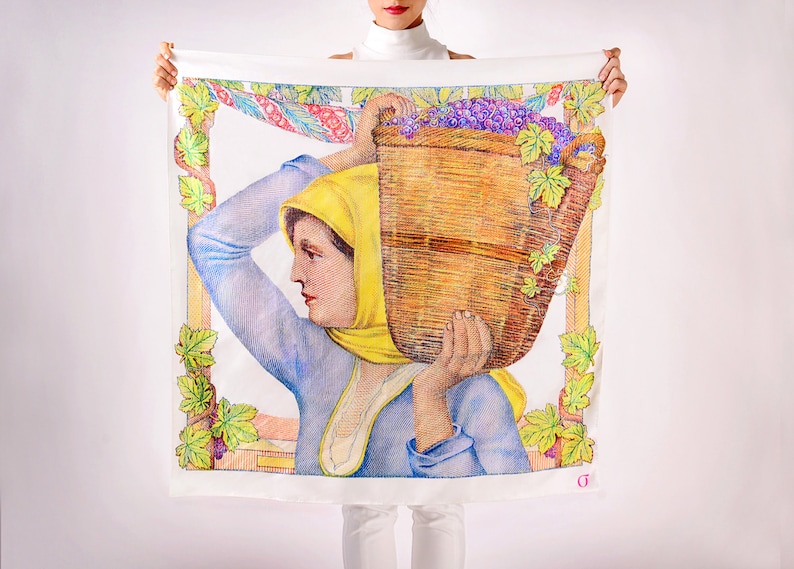May include: White square scarf with a detailed illustration of a woman carrying a basket of grapes. The woman wears a yellow headscarf and blue shirt. The border includes grape vines and a decorative frame.