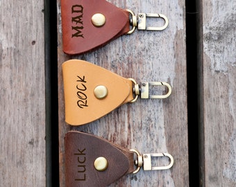 May include: Three leather keychains with metal clasps. The keychains are triangular in shape and have the words "Mad", "Rock", and "Luck" engraved on them.
