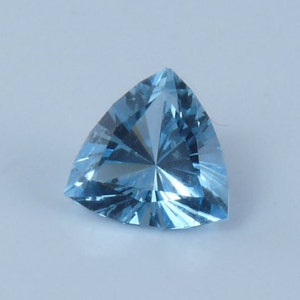 May include: A triangular, light blue gemstone with a faceted cut.