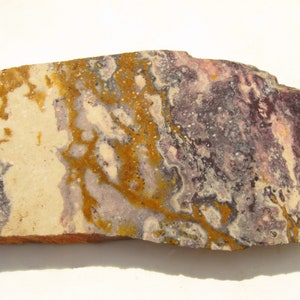 May include: A slab of polished agate with a swirling pattern of white, purple, and yellow.