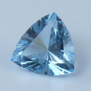 May include: A triangular, light blue gemstone with a faceted cut.