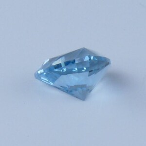 May include: A light blue gemstone with a faceted cut. The gemstone is on a white background.