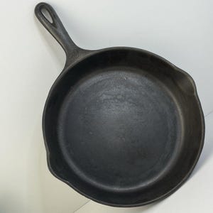 May include: A black cast iron skillet with a loop handle. The skillet is seasoned and ready to use.