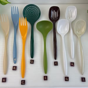 May include: A collection of nine kitchen utensils in various colors and shapes, including forks, a skimmer, a ladle, and slotted spoons. Each item is labeled with a small square tag featuring a letter and number, such as A1, B3, C3, D2, E1, F4, G3, H4, and I1.