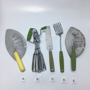 Puede incluir: Cinco utensilios de cocina con mangos verdes y amarillos. Los utensilios incluyen una espátula, un batidor, un cuchillo para mantequilla, un tenedor y una cuchara ranurada.