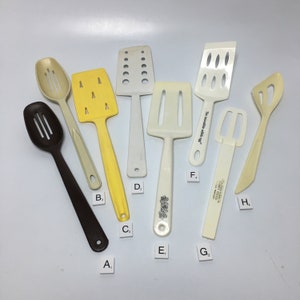 Puede incluir: Un juego de ocho utensilios de cocina, que incluyen espátulas, cucharas y una cuchara ranurada. Los utensilios están hechos de plástico blanco y amarillo. Los utensilios están etiquetados con las letras A a H.