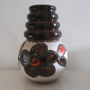 May include: A brown and white ceramic vase with a geometric pattern of flowers. The vase has a wide base and a narrow neck with a series of brown rings.