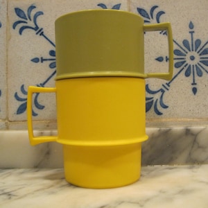 Könnte beinhalten: Eine gelbe und grüne Plastiktasse mit Henkel. Die Tasse besteht aus zwei übereinander gestapelten Teilen.
