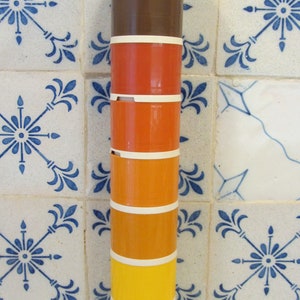 May include: A stackable set of six colourful canisters with a white base. The canisters are stacked in a tower and are made of plastic. The colours of the canisters are green, brown, orange, yellow, and white.