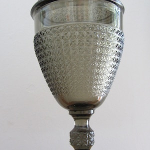 May include: A gray glass candy dish with a lid. The dish has a diamond pattern and a pedestal base.