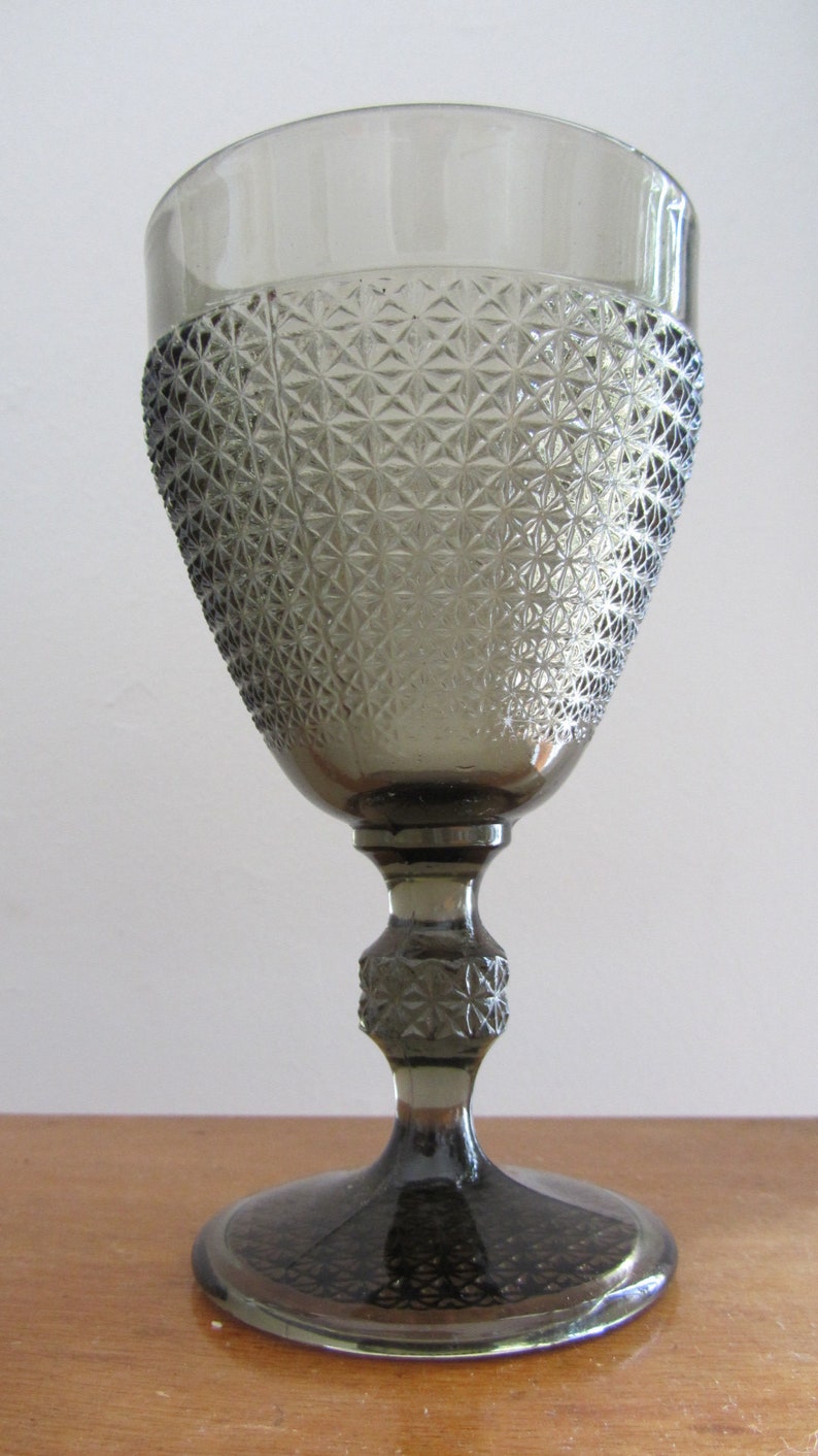 May include: A gray glass goblet with a diamond pattern. The goblet has a tall stem and a wide base.