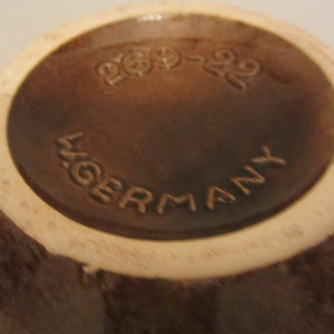 May include: A brown ceramic bowl with a white rim. The bottom of the bowl has the text "200-220" and "W. GERMANY" printed on it.