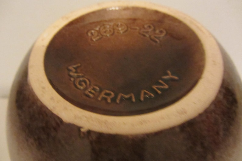 May include: A brown ceramic bowl with a white rim. The bottom of the bowl has the text "200-220" and "W. GERMANY" printed on it.