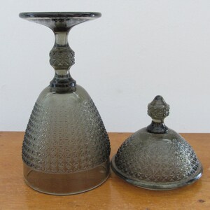 May include: A set of two gray glass serving dishes with a textured diamond pattern. The dishes have a dome lid and a base with a pedestal.