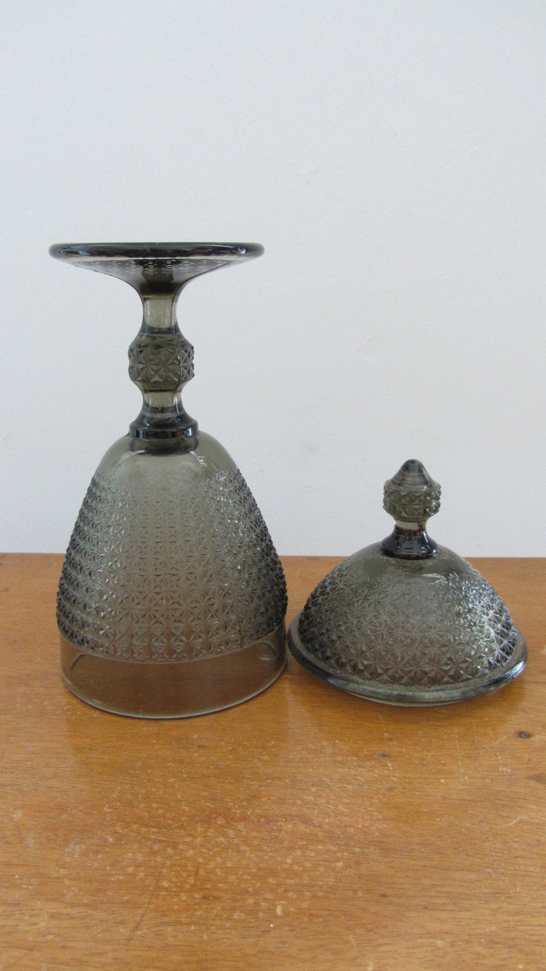 May include: A set of two gray glass serving dishes with a textured diamond pattern. The dishes have a dome lid and a base with a pedestal.