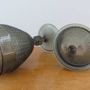 May include: A set of two clear glass bowls with a textured, diamond-shaped pattern. The bowls are a dark gray color and have a stem.