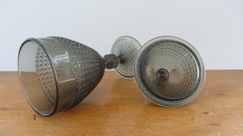 May include: A set of two clear glass bowls with a textured, diamond-shaped pattern. The bowls are a dark gray color and have a stem.