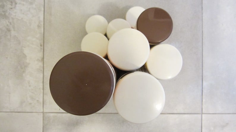 May include: A set of eight round containers with alternating white and brown lids. The containers are stacked in a pyramid shape.