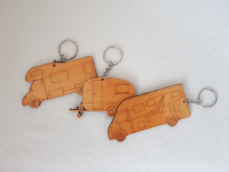 Puede incluir: Tres llaveros de madera con forma de autocaravana. Cada llavero tiene un anillo de metal plateado.